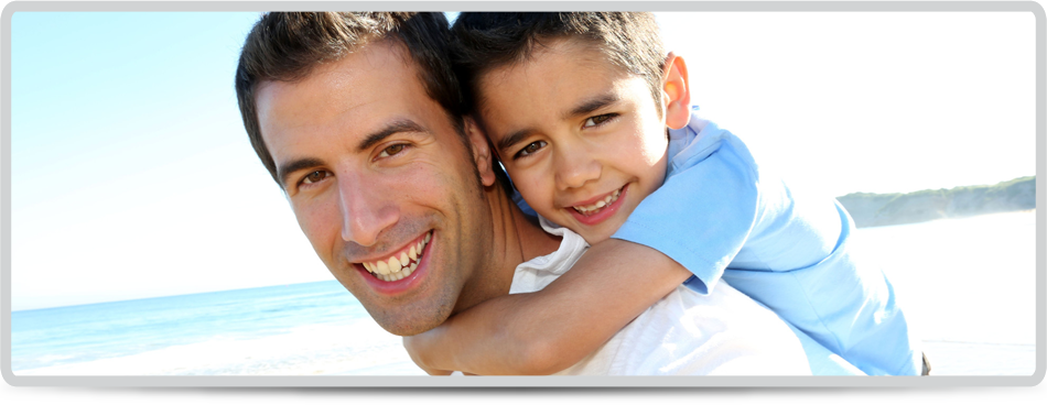 Child cuddling man and both smiling near the beach